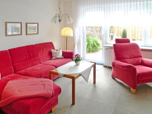 uma sala de estar com um sofá vermelho e duas cadeiras em Apartment Dehne-1 by Interhome em Norddeich
