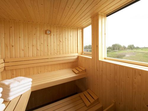 a wooden sauna with a window and towels in it at Villa Krekt Oer 't Wetter by Interhome in Uitwellingerga