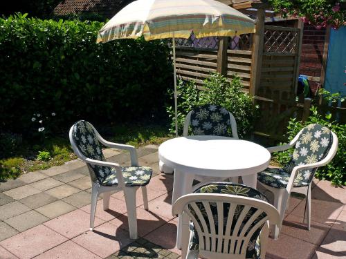 3 chaises et une table avec un parasol dans l'établissement Holiday Home Schäfer by Interhome, à Norden