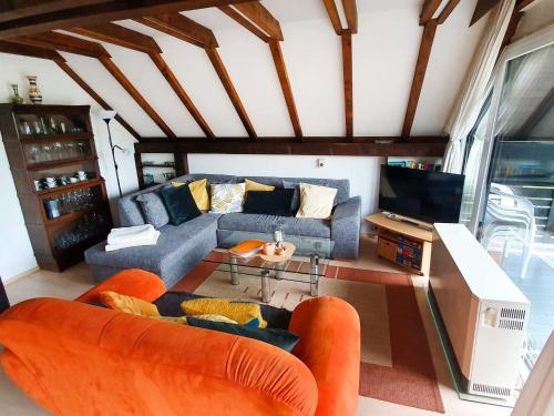 a living room with orange chairs and a couch at Holiday Home Ferienpark Vorauf-4 by Interhome in Molberting