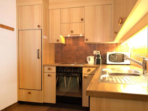 a kitchen with wooden cabinets and a sink and a stove at Apartment Chesa Corvatsch by Interhome in Pontresina