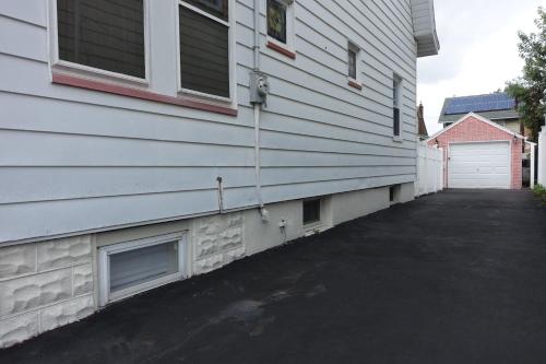 a white house with a driveway next to a garage at Best EWR Airport Apt-Hot Tub-Free Parking in Hillside