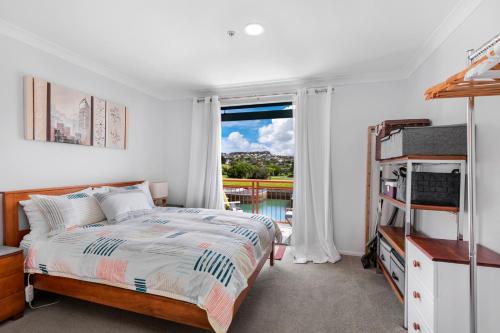 1 dormitorio con cama y ventana en Harbourside Haven - Whangaparāoa Studio Apartment, en Te Whanga