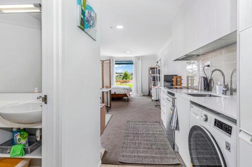 una cocina con encimeras blancas y fregadero en Harbourside Haven - Whangaparāoa Studio Apartment, en Te Whanga