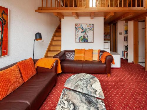 a living room with leather couches and a staircase at Apartment Chalet Abendrot-19 by Interhome in Grindelwald