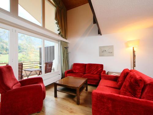 a living room with red furniture and a large window at Apartment Ringstrasse - Utoring-51 by Interhome in Leukerbad