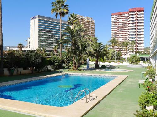 a large swimming pool with palm trees and buildings at Apartment Esmeralda-1 by Interhome in Calpe