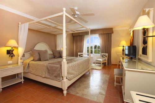Bahia Principe Grand Samana - Adults Only في سانتا باربرا دو سامانا: غرفة نوم بسرير مظلة وتلفزيون