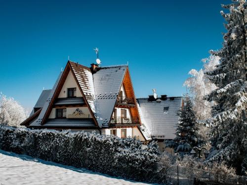 a house in the snow with a tree at Willa Pachówka - tam, gdzie natura spotyka się z nowoczesnością in Bukowina Tatrzańska