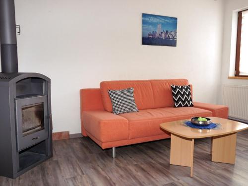 a living room with an orange couch and a stove at Apartment Camping Rossbach-1 by Interhome in Nassereith