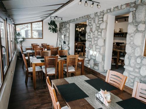 a restaurant with wooden tables and chairs and a stone wall at Willa Pachówka - tam, gdzie natura spotyka się z nowoczesnością in Bukowina Tatrzańska