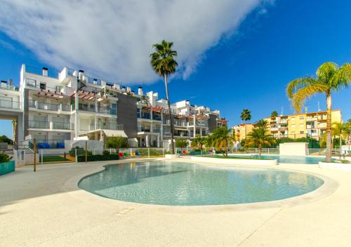 una piscina frente a un edificio con palmeras en Apartamento Victoria Playa III con una gran terraza, en Denia