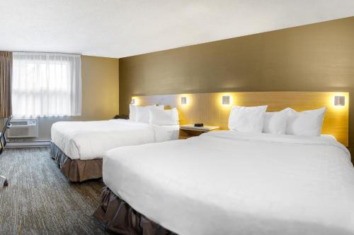 a hotel room with two beds and a window at Clarion Pointe Quebec Airport in Quebec City