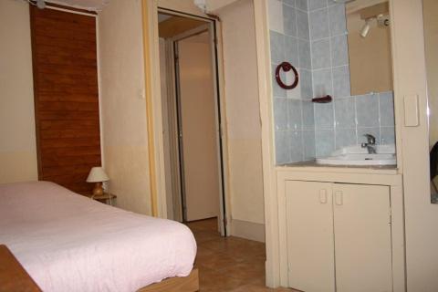 Schlafzimmer mit einem Bett, einem Waschbecken und einem Spiegel in der Unterkunft LE GÎTE LES MELEZES in Villar-dʼArène
