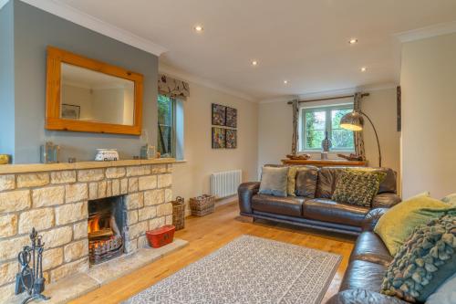 a living room with a couch and a fireplace at Woodside Cottage in Chipping Campden
