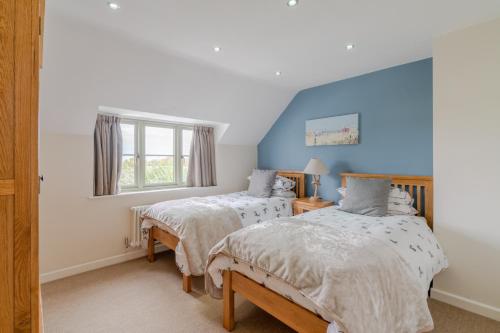 a bedroom with two beds and a window at Woodside Cottage in Chipping Campden