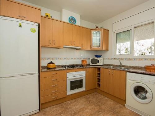 a kitchen with wooden cabinets and a white refrigerator at Holiday Home Juan by Interhome in Segur de Calafell