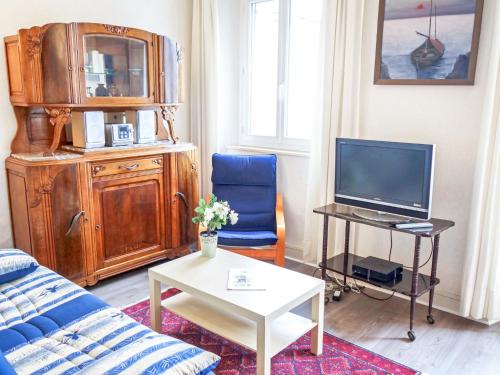 a living room with a blue couch and a tv at Apartment Beauchesne by Interhome in Saint Malo