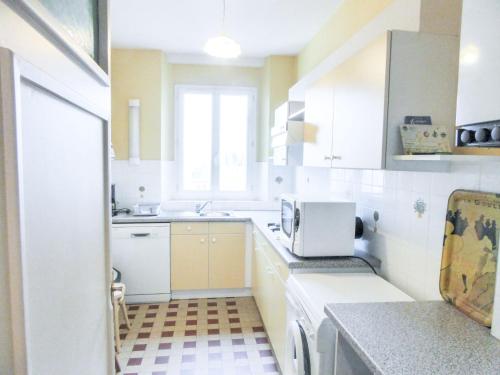 une petite cuisine avec des armoires blanches et un micro-ondes dans l'établissement Apartment Beauchesne by Interhome, à Saint-Malo