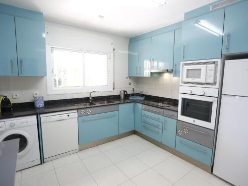 cocina con armarios azules, lavadora y secadora en Holiday Home Annamaria by Interhome, en Vilafortuny
