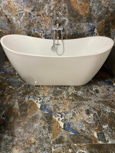 a white bath tub sitting on top of a marble floor at Dom Malowy Sad in Zalesie