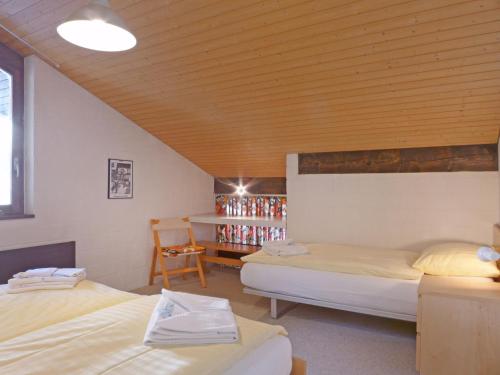 ヴェンゲンにあるApartment Im Gruebi-1 by Interhomeのベッド2台と棚(ボトル付)が備わる客室です。