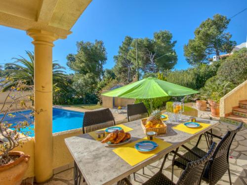 a table with a green umbrella on a patio at Holiday Home Flamenc by Interhome in Jávea