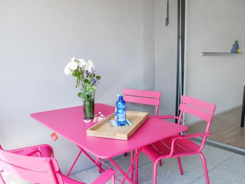 a pink table with pink chairs and a vase of flowers at Apartment LaVille A-3-4 by Interhome in Locarno
