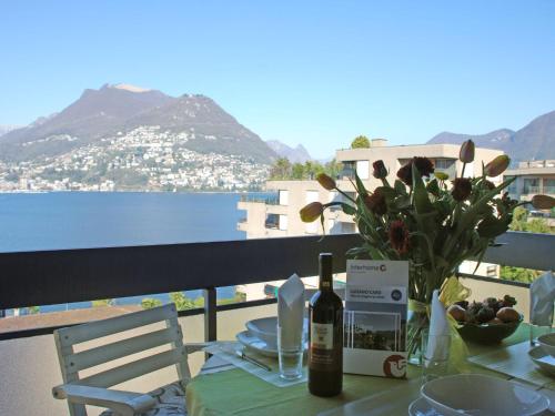 - une table avec une bouteille de vin et un vase de fleurs dans l'établissement Apartment App- Paradiso by Interhome, à Paradiso