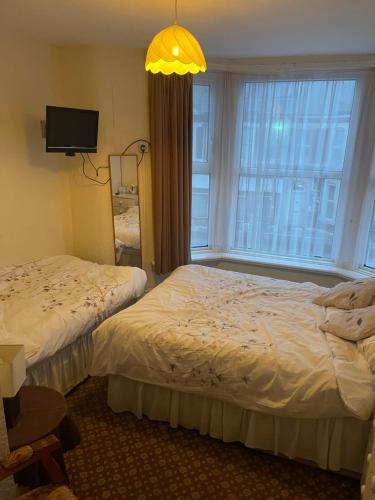 a hotel room with two beds and a window at Highbury Hotel in Blackpool