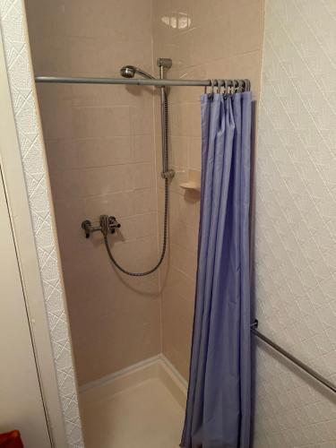 a shower with a blue shower curtain in a bathroom at Highbury Hotel in Blackpool