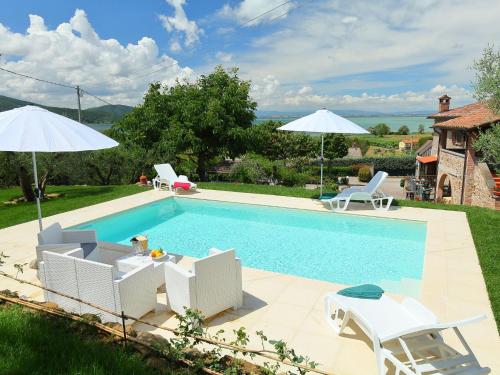 a swimming pool with white chairs and umbrellas at Holiday Home Trasimeno link by Interhome in San Savino