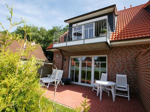 ノルトダイヒにあるApartment Westerriede by Interhomeのレンガ造りの家の上に椅子とテーブル付きのパティオ