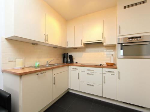 ブレーデネにあるApartment Residentie Zeeparel by Interhomeのキッチン(白いキャビネット、ステンレス製の電化製品付)