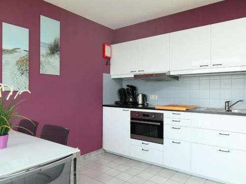 a kitchen with white cabinets and a purple wall at Studio Residentie Astrid-5 by Interhome in Bredene