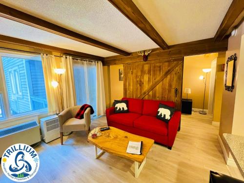 a living room with a red couch and a table at Rustic Mountainside Chalet in Blue Mountains