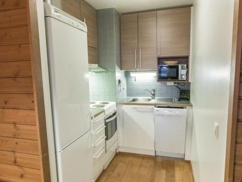 una cocina con electrodomésticos blancos y armarios de madera en Holiday Home Ylläs chalets a202 by Interhome, en Ylläs
