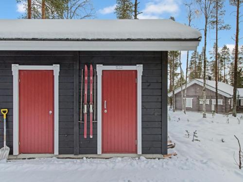 zwei rote Türen an einem Gebäude mit Skiern im Schnee in der Unterkunft Holiday Home Luppo by Interhome in Ylläsjärvi