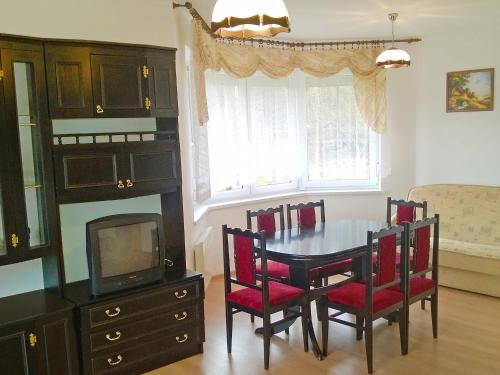 une salle à manger avec une table, des chaises et une télévision dans l'établissement Holiday Home Smołdziński Las by Interhome, à Smołdziński Las