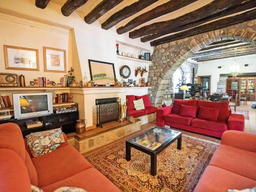 a living room with red furniture and a stone fireplace at Holiday Home Can Trullas by Interhome in Viladecaballs