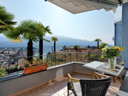 a balcony with a table and chairs and palm trees at Apartment Double Room Classic-1 by Interhome in Ascona