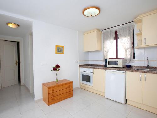 une cuisine avec des placards blancs et un vase de fleurs sur une table dans l'établissement Apartment Topacio IV-1 by Interhome, à Calp