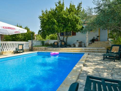a blue swimming pool with two chairs and an umbrella at Holiday Home Villa Ana by Interhome in Kruševo