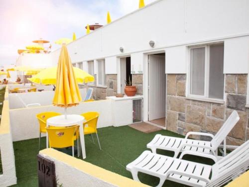um pátio com cadeiras amarelas e brancas e um guarda-sol em Apartment Estudio by Interhome em Sintra
