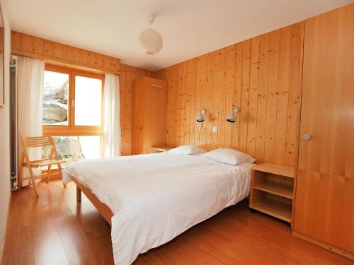 オヴロナにあるApartment Fénestral R01 by Interhomeの白いベッドと木製の壁が備わるベッドルーム1室が備わります。