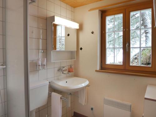 a white bathroom with a sink and a mirror at Chalet Bühlweidli by Ferienlenk in Lenk