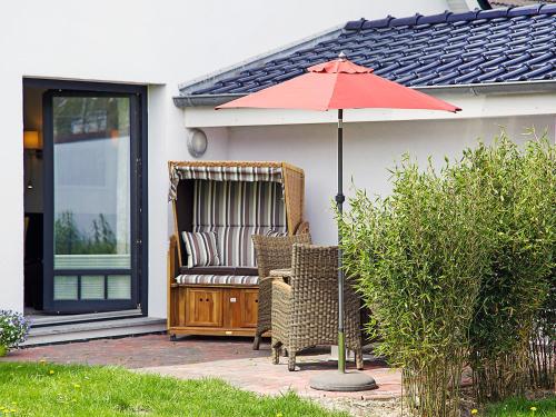a patio with two chairs and an umbrella at Apartment Witthuus-Borkum by Interhome in Norddeich