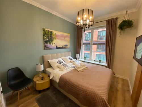 a bedroom with a bed with a chair and a chandelier at Apartament rodzinny in Gdańsk