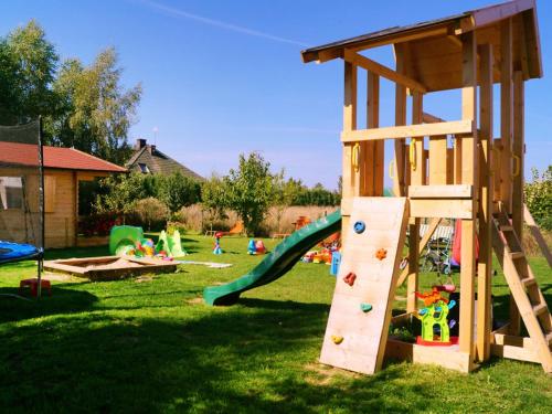 a playground with a slide and play equipment in the grass at Holiday Home Villa Amber Gąski-2 in Gąski