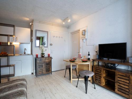 ein Wohnzimmer mit einem Tisch und einem TV sowie eine Küche in der Unterkunft Apartment Le Curling B - Val Claret-30 by Interhome in Tignes